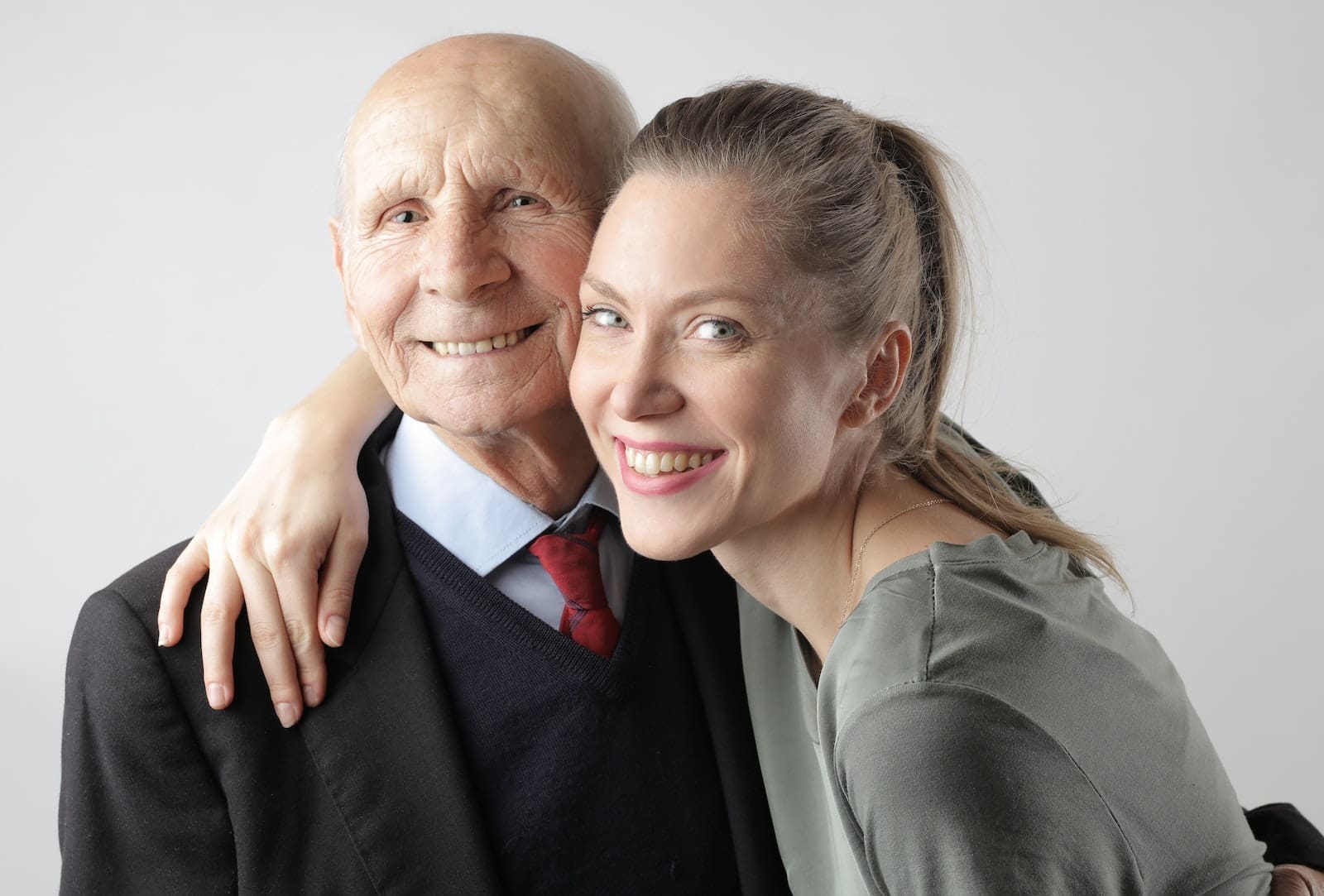 Father' Day, Cheerful elderly man and adult woman cuddling on white background and looking at camera