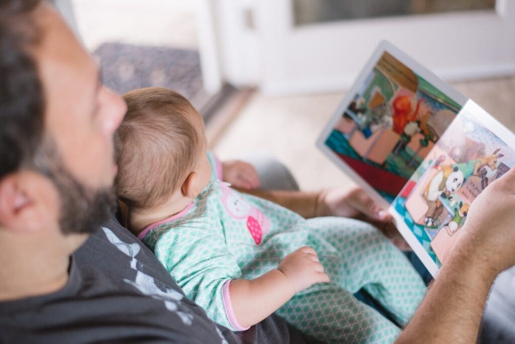 Father carrying baby while reading book