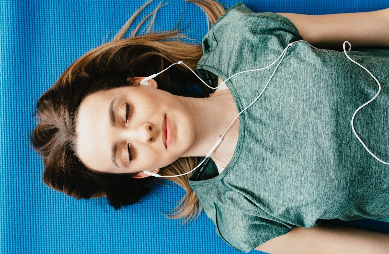 5 Key Trends Reshaping Streaming Audio Over the Past Decade. Tranquil woman resting on yoga mat in earphones at home